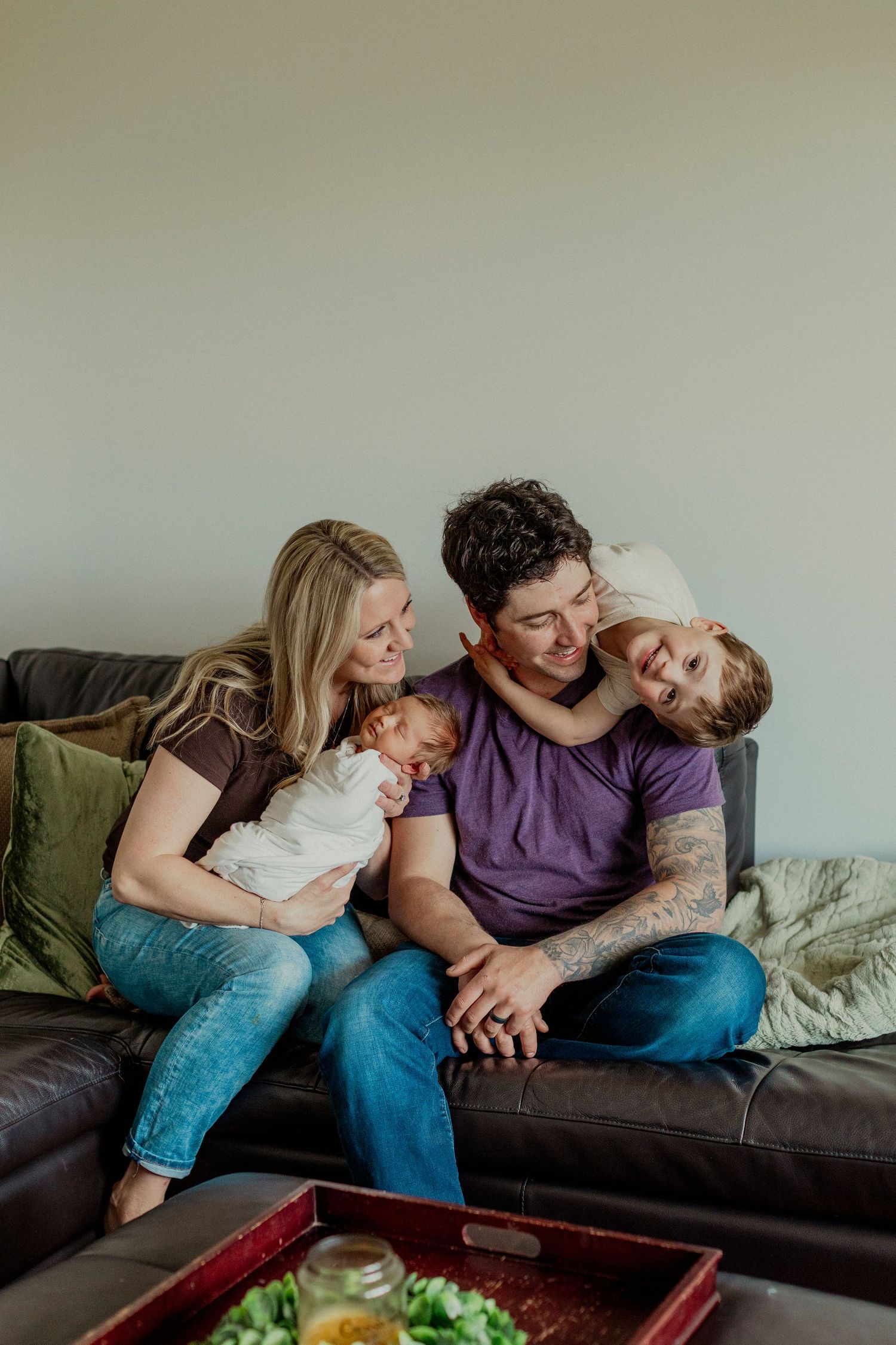 A family shares a joyful moment together while relaxing on their brown leather couch at home.