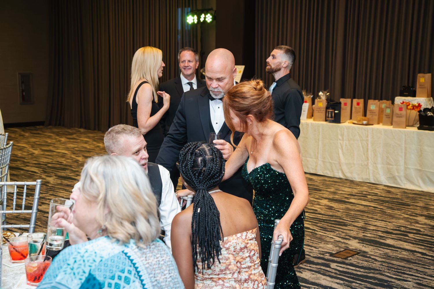 Wedding guests dance and celebrate on a crowded dance floor at an indoor reception venue.