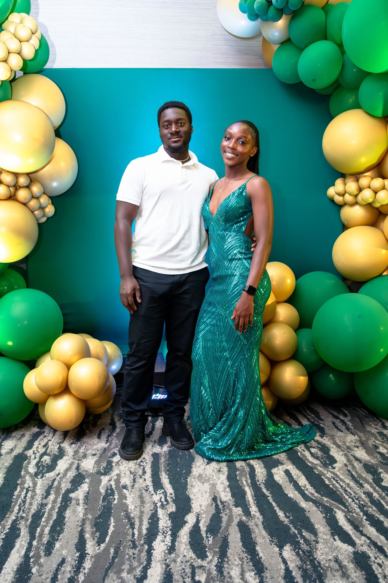 A couple poses against a festive backdrop of green and gold balloons in a four-panel photo series.