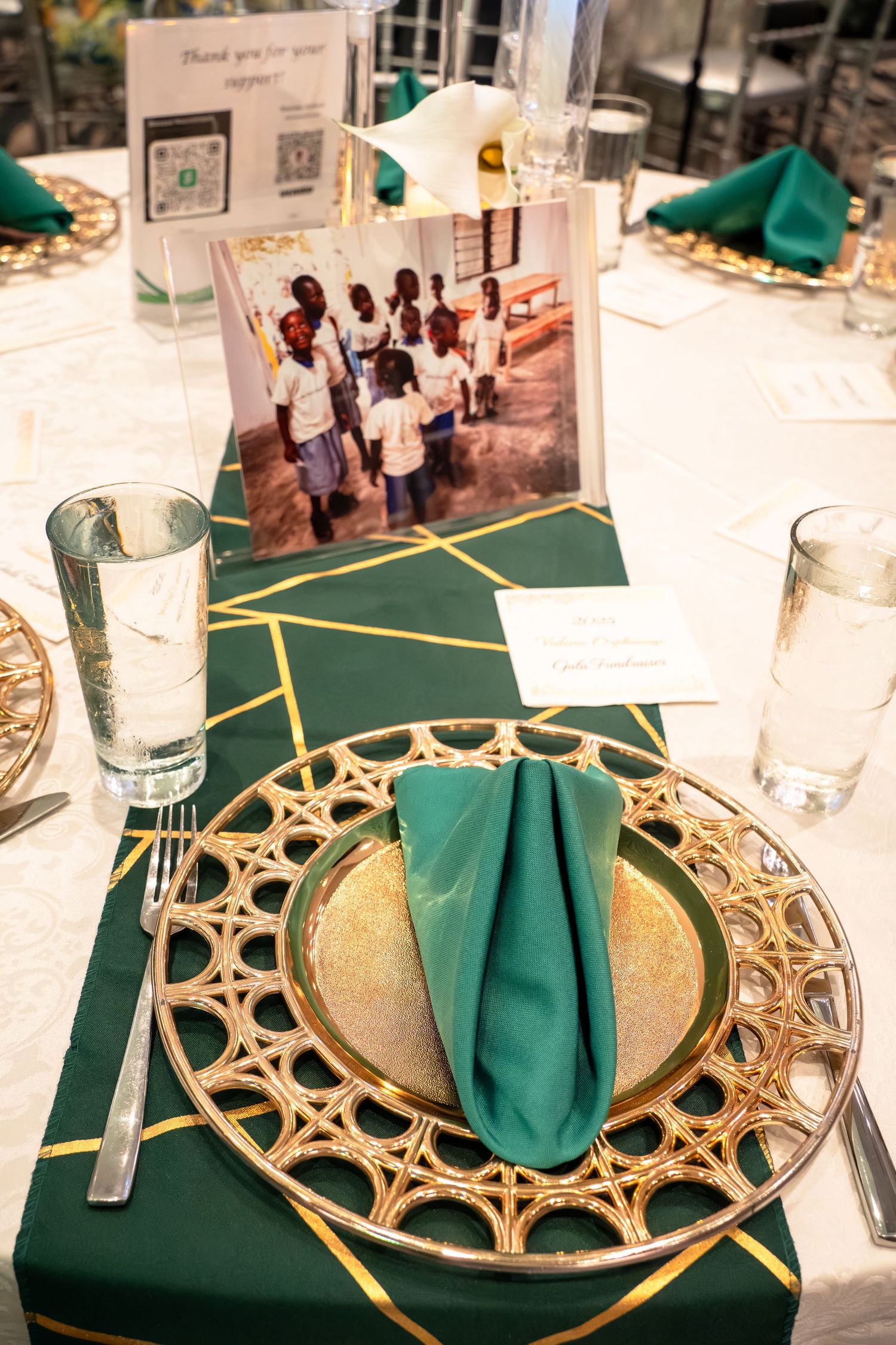 Elegant table settings with green napkins and ornate gold charger plates arranged for a formal dining event.