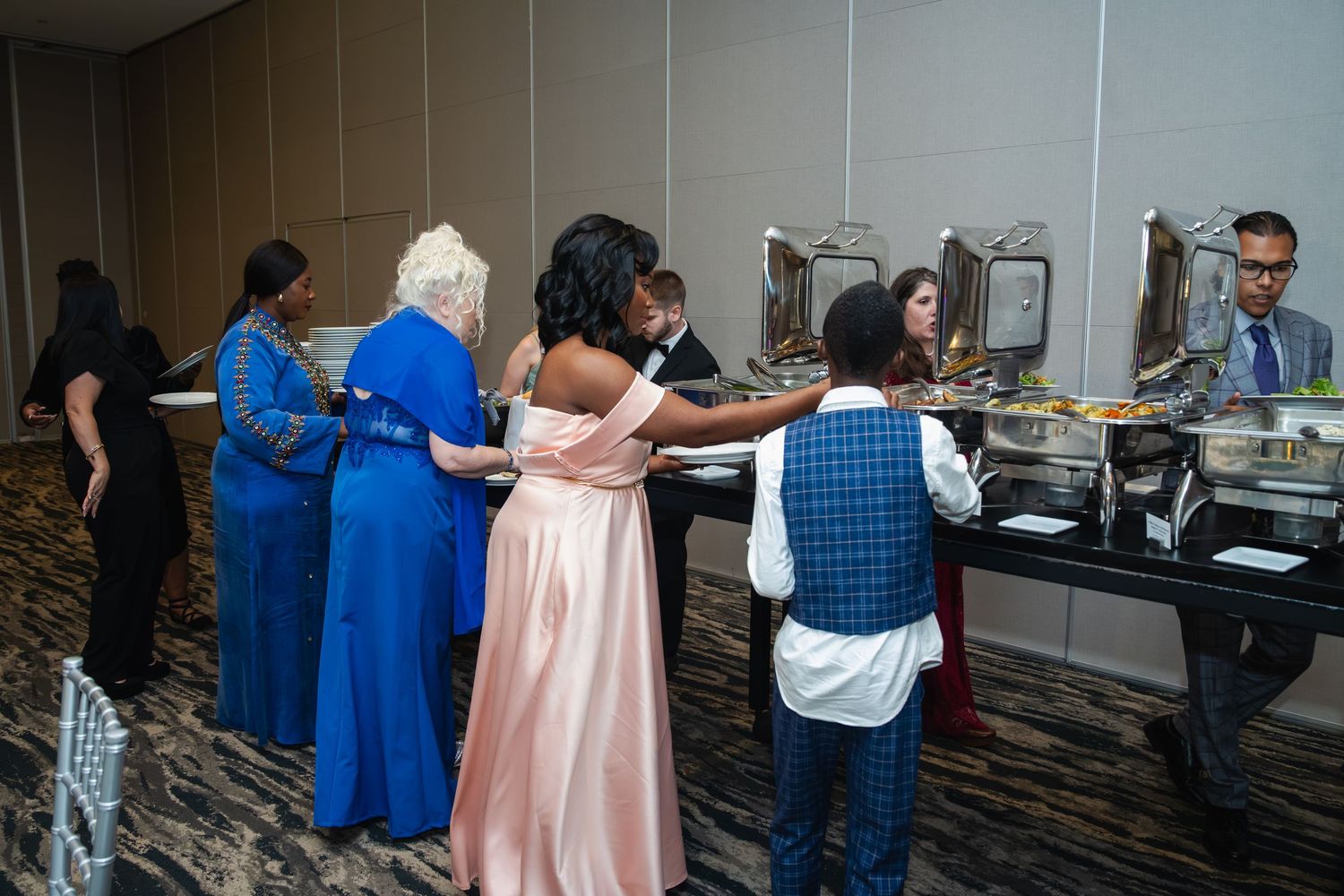 People standing in line at a registration or check-in desk during an indoor event.