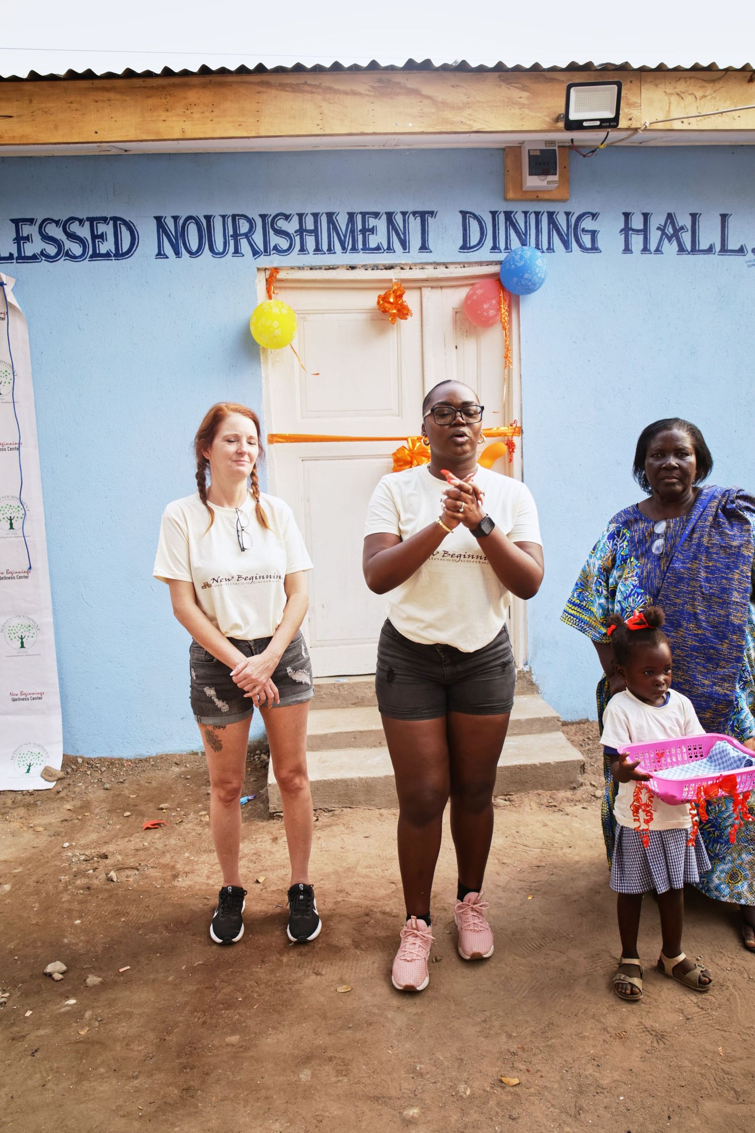 Group posed in front of Blessed Nourishment Dining Hall entrance with colorful balloon decorations.