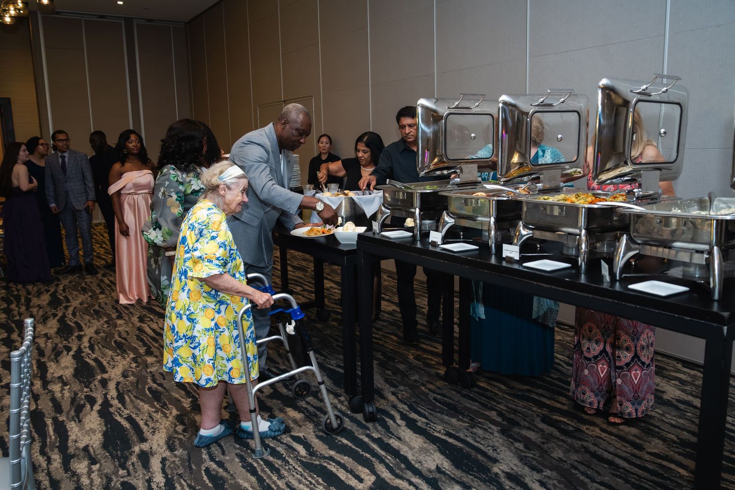 Conference attendees gather in an elegant hotel ballroom with modern decor and carpeting.