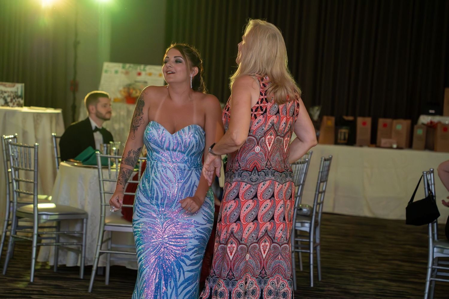 People dancing and celebrating at a festive event in a decorated indoor venue with bright lighting.