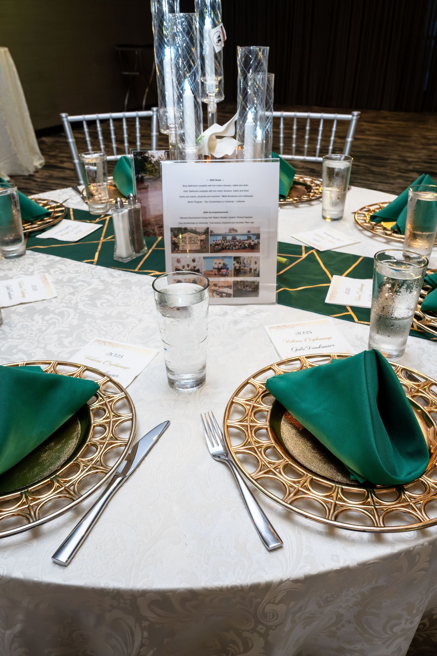 Elegant table settings with emerald green napkins and gold charger plates on white tablecloths at a formal event.
