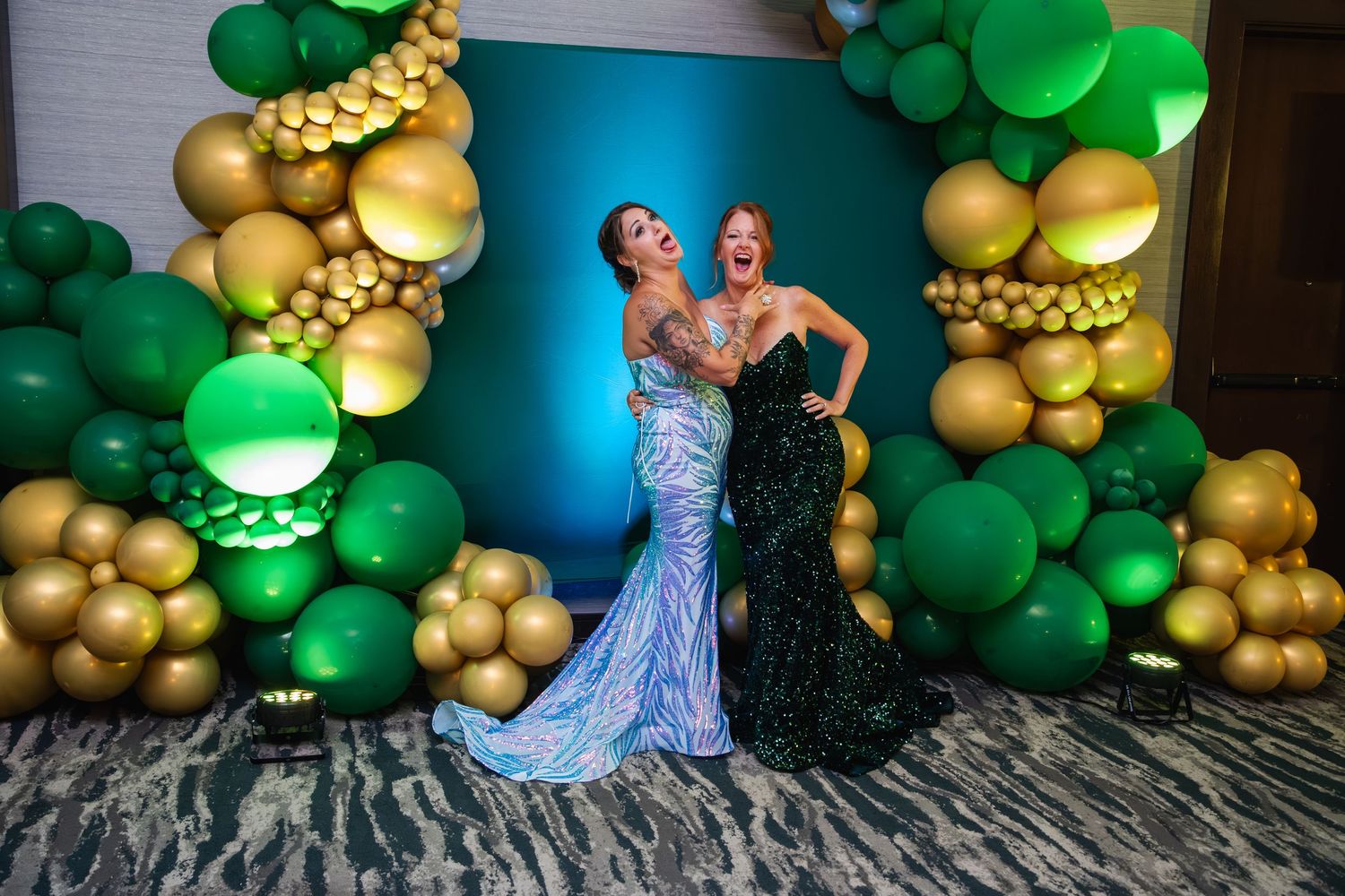 A festive party backdrop featuring green and gold balloon garlands against a dark wall creates an elegant celebration atmosphere.