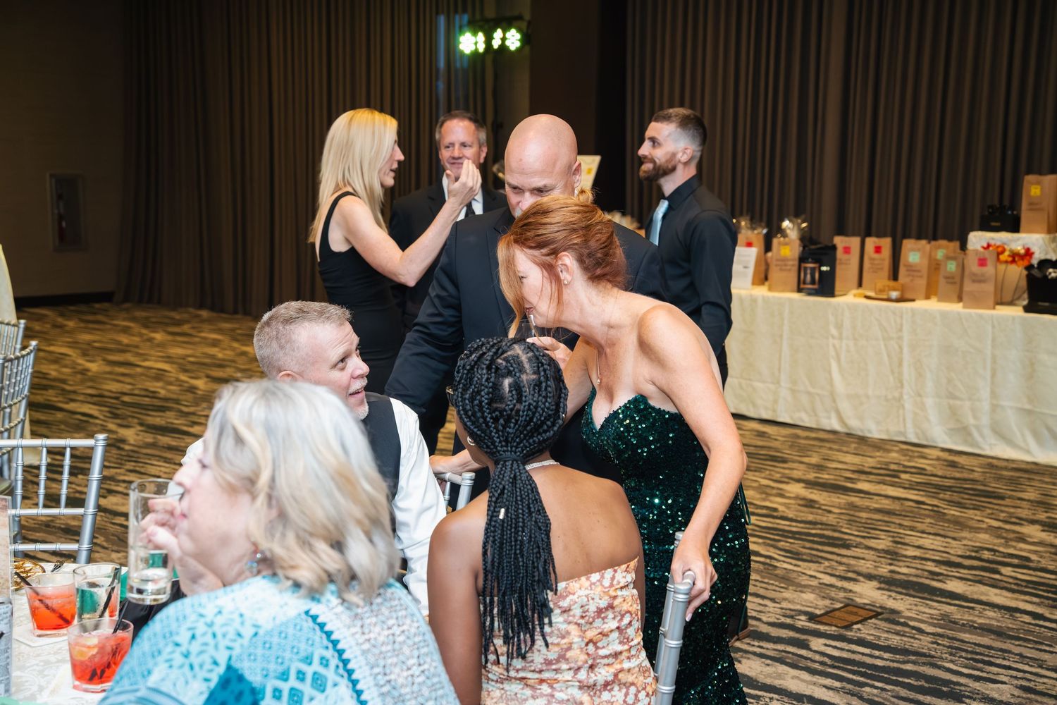 Wedding guests dancing and socializing at a reception in an elegant ballroom with white decor.