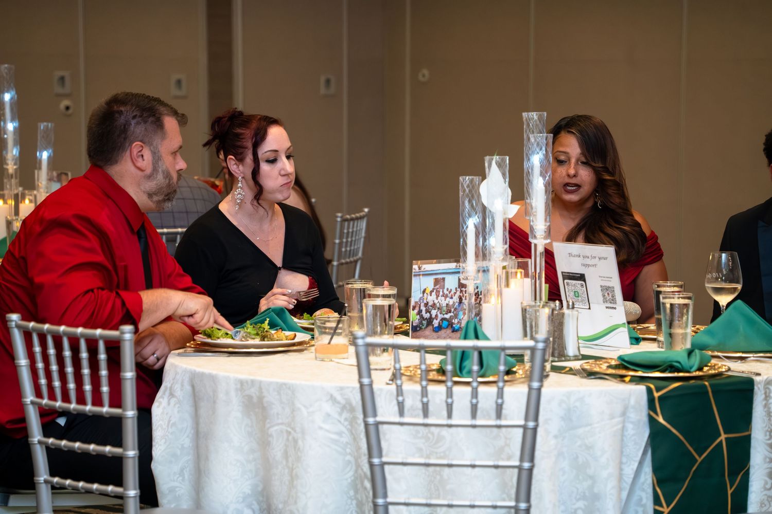 Guests seated at elegant banquet tables with white linens and chiavari chairs during a formal dining event.