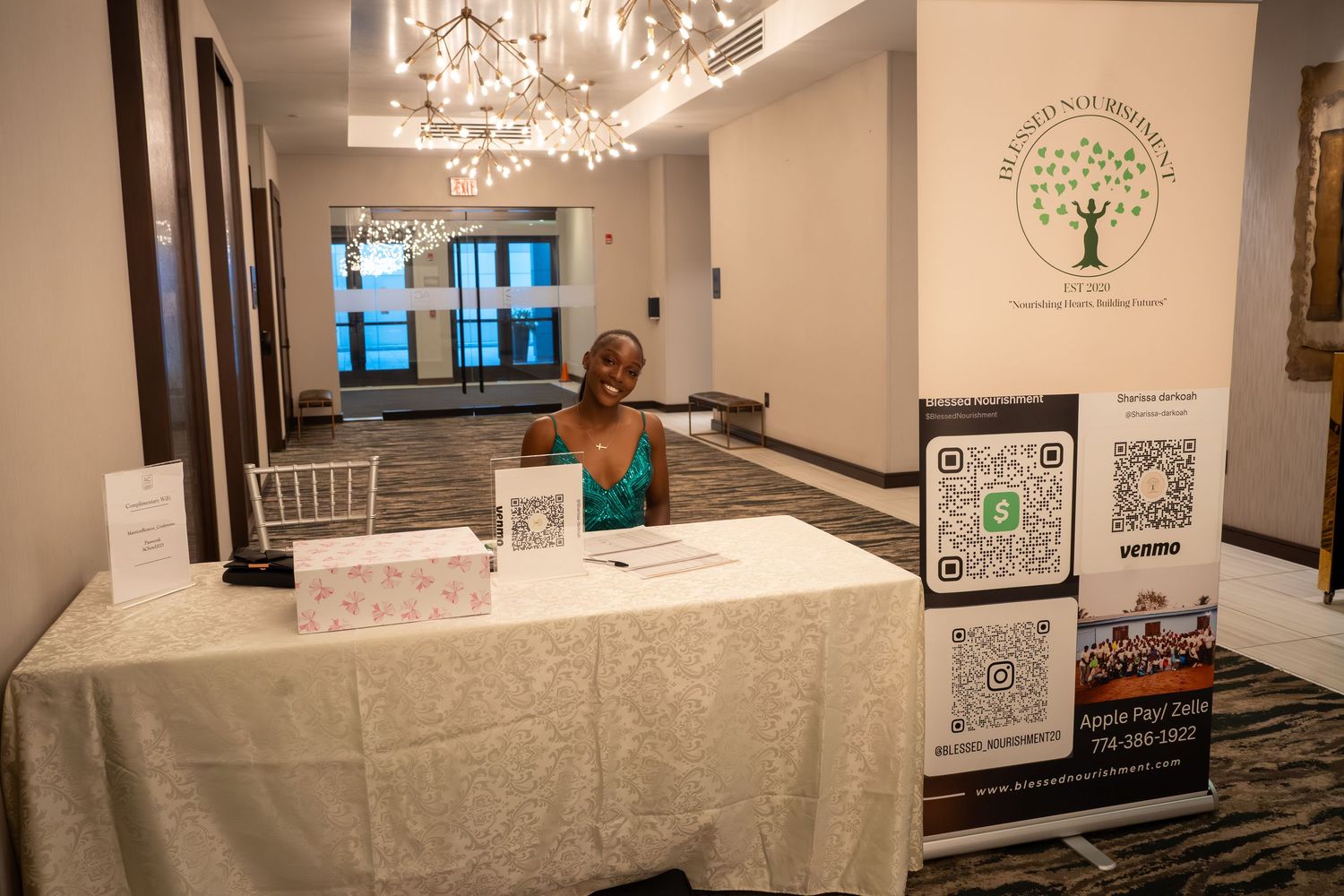 Elegant event space with white tablecloths and crystal chandeliers showcasing framed artwork on display.