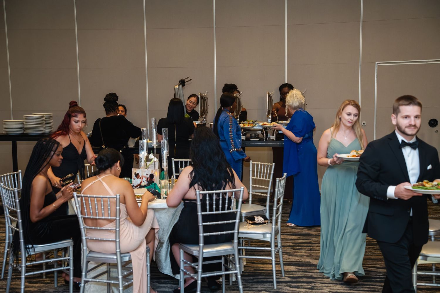Wedding guests enjoy dancing and mingling at an elegant reception with white Chiavari chairs.