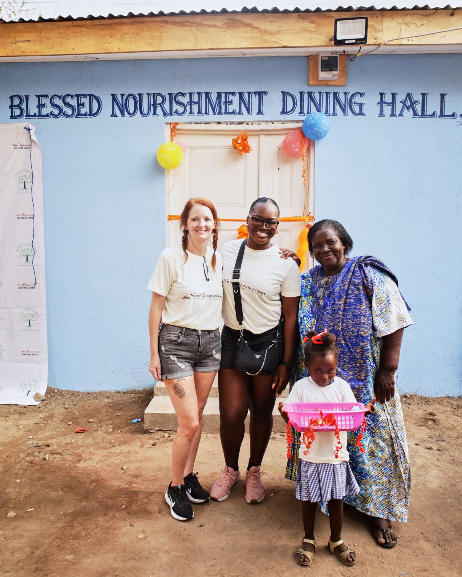 Group photo outside Blessed Nourishment Dining Hall decorated with colorful balloons.