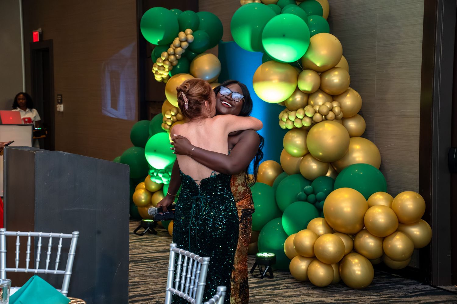 A festive party setup with green and gold balloon garlands decorating a doorway and interior space.