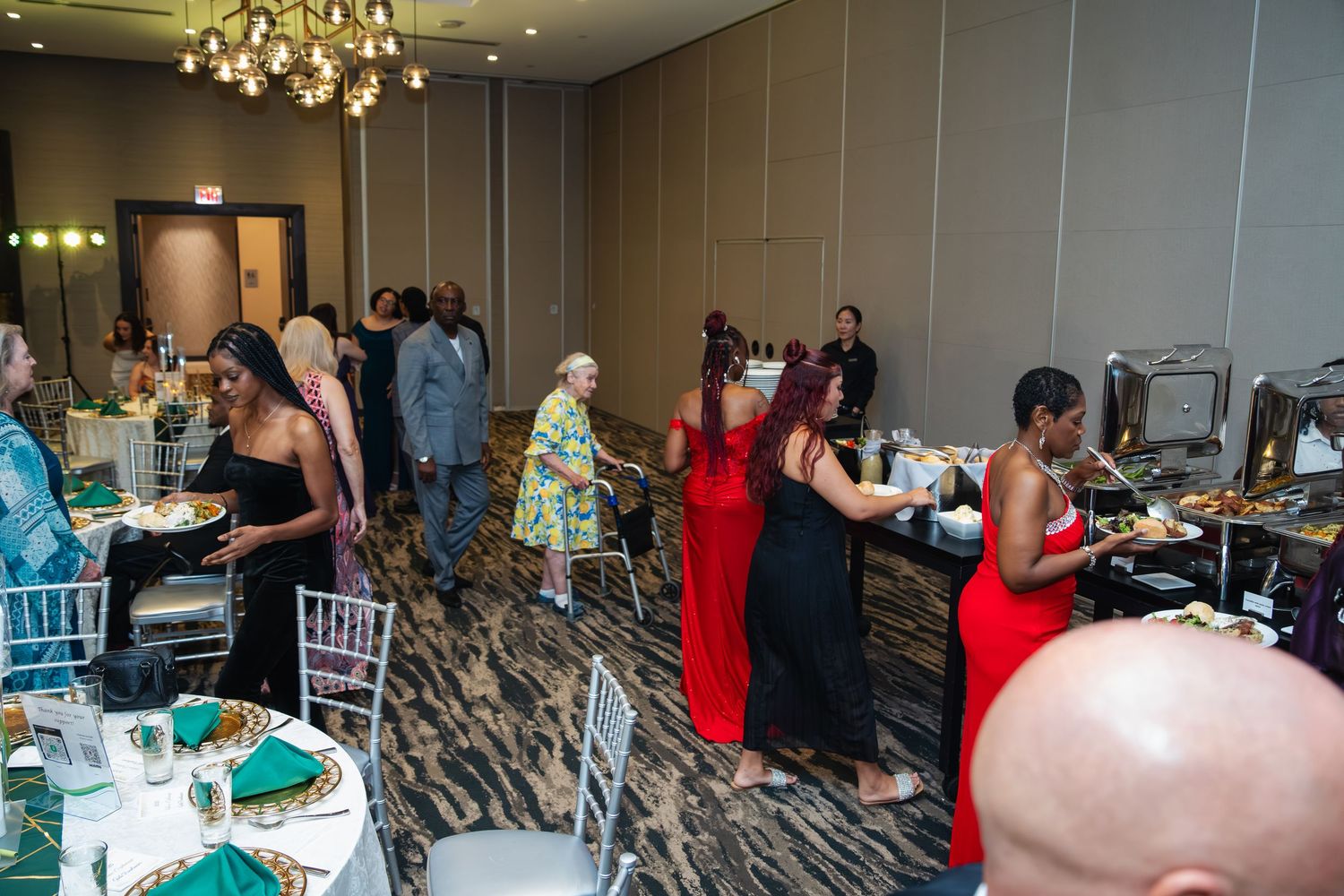 A large group of people seated at elegant tables in a banquet hall with chandeliers and formal decor.