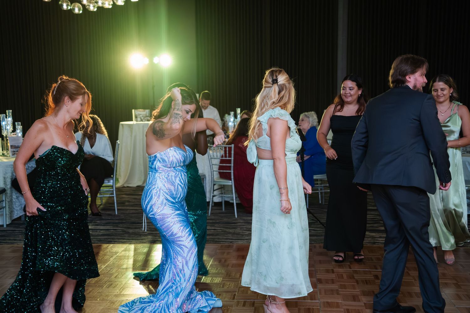 People dancing together at an evening reception or party with green lighting and formal attire.