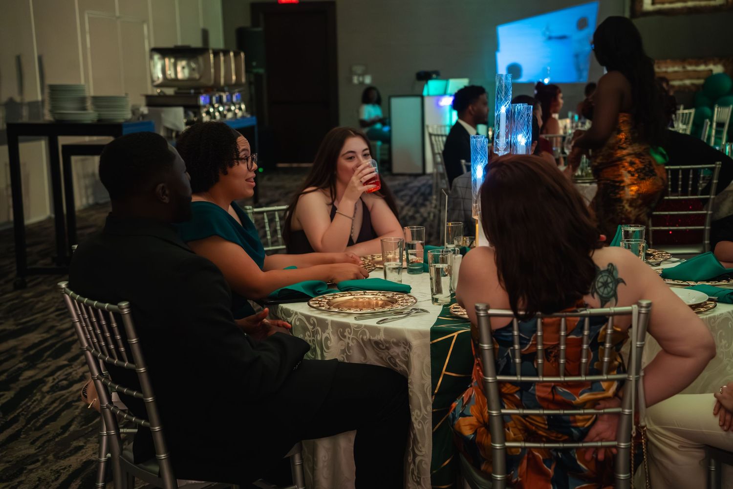 People gathered around tables in a dimly lit venue for a social event or celebration.