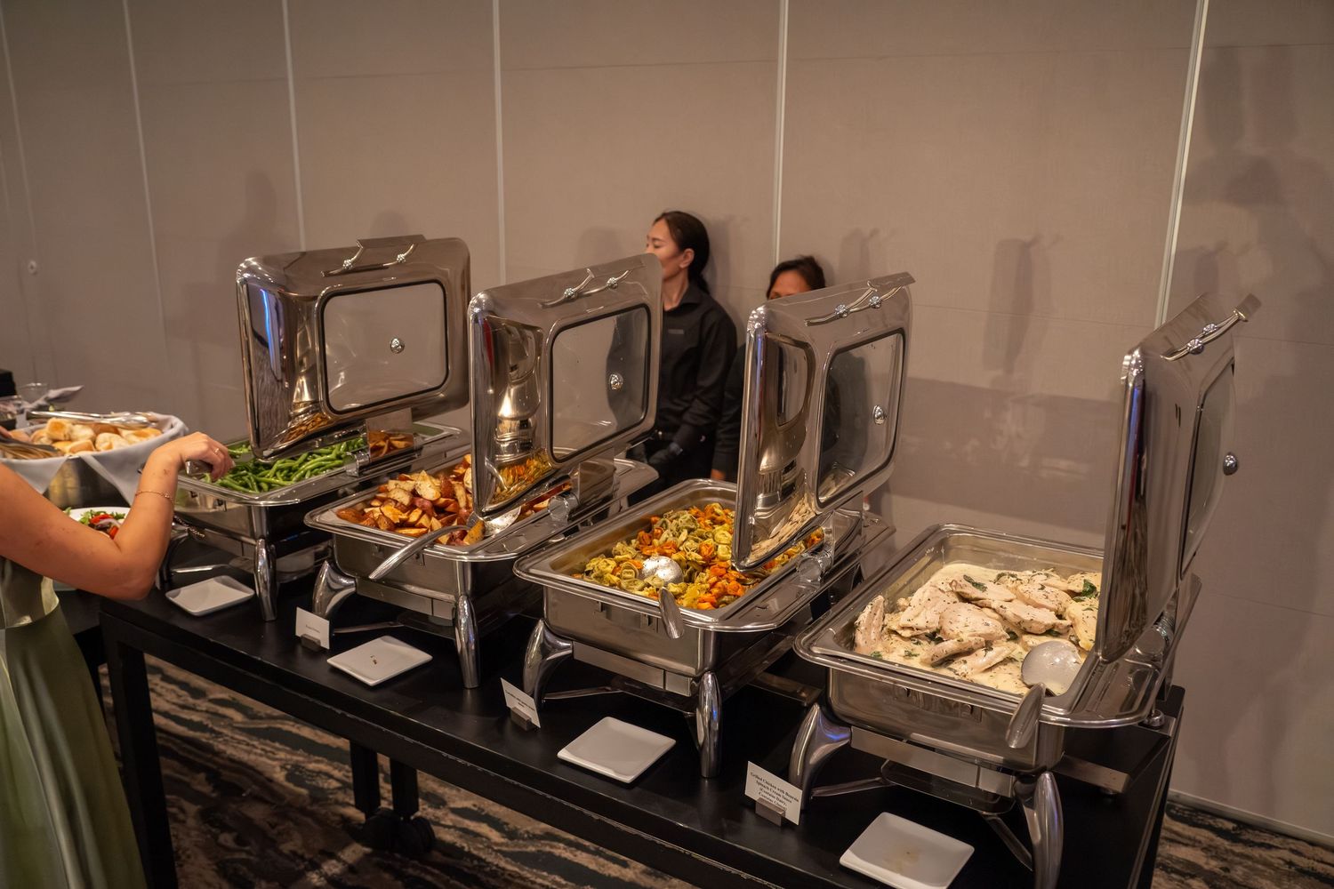 A buffet line with stainless steel chafing dishes and food warmers displays various prepared dishes for service.