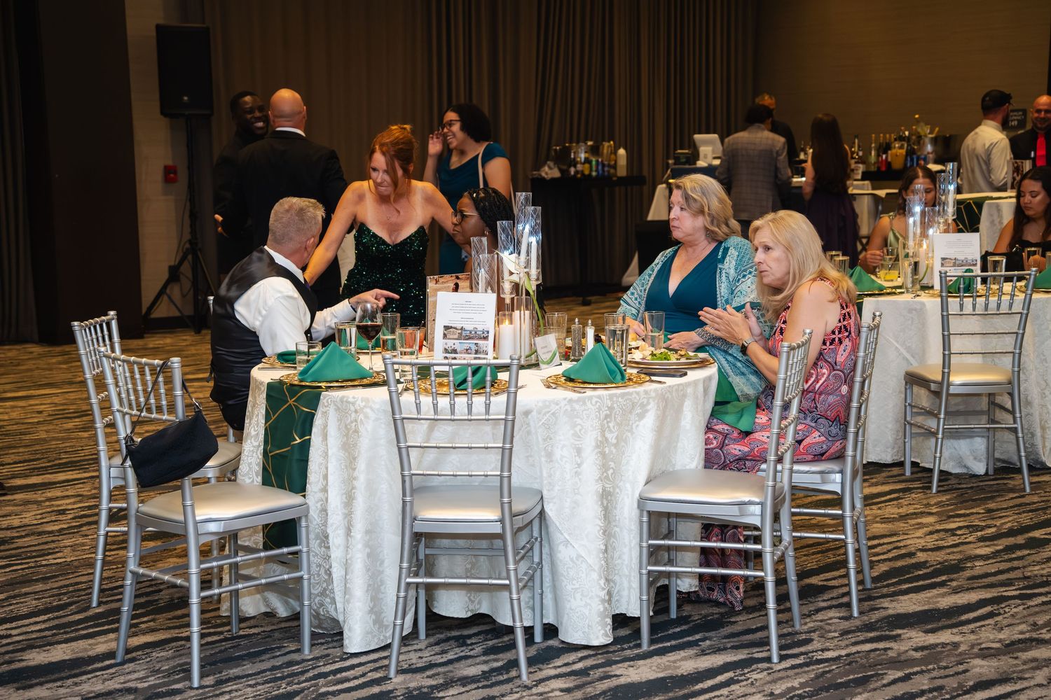 Panoramic view of guests seated at elegant white-clothed dining tables during a formal event in a banquet hall.
