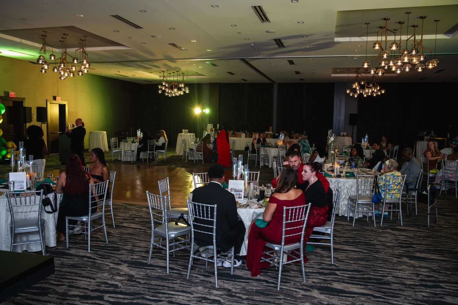 Elegant banquet hall interior with crystal chandeliers, round tables, and chairs set up for an event.