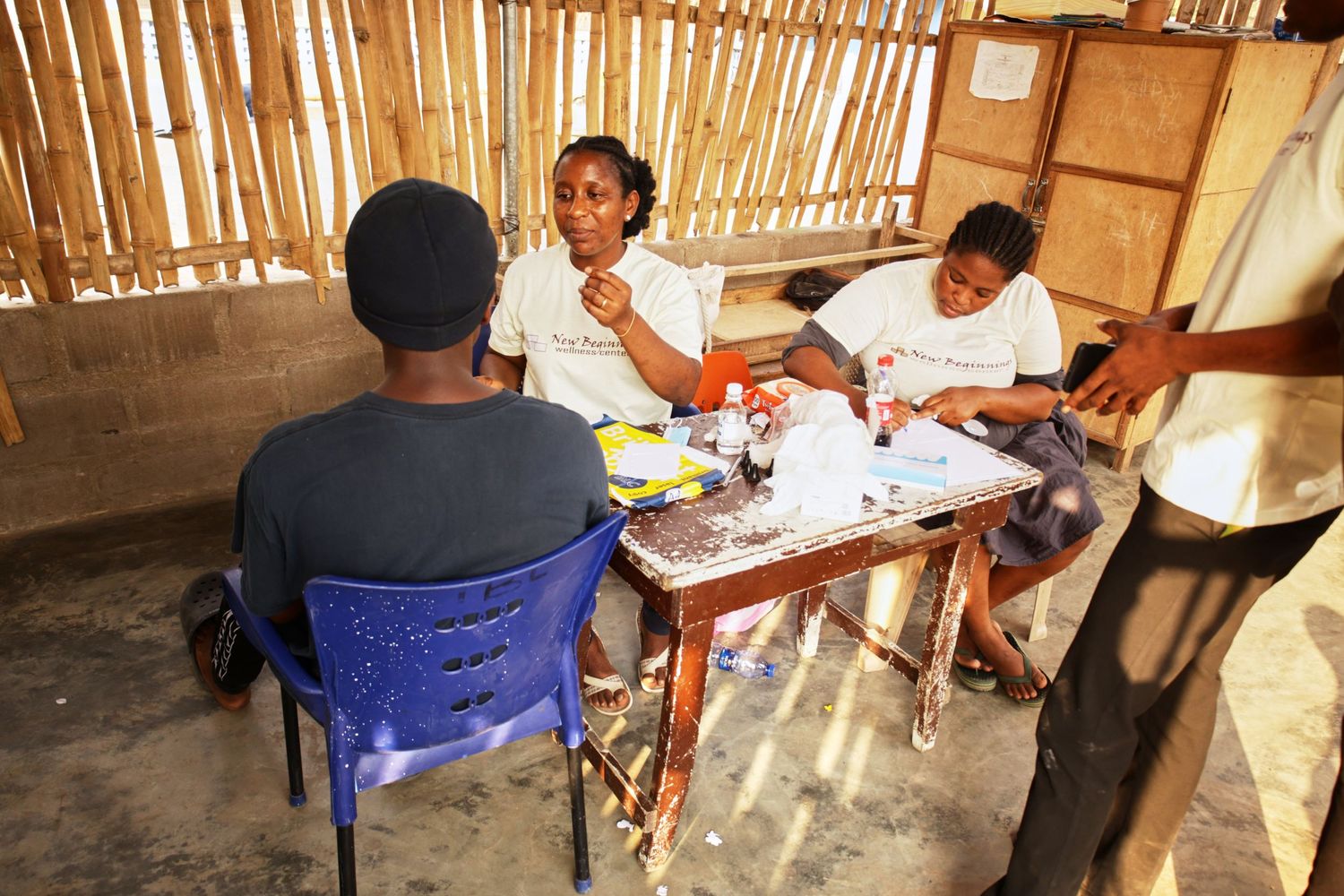 Students participate in learning activities at a table in bamboo-walled classroom.