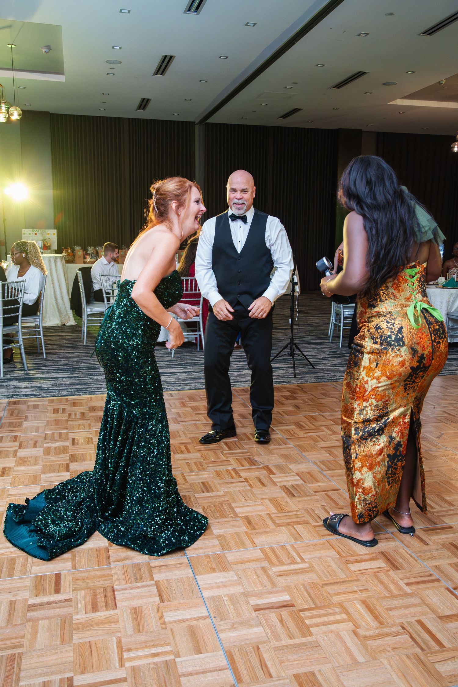 People dancing and celebrating on a parquet dance floor at a formal event with elegant decor.