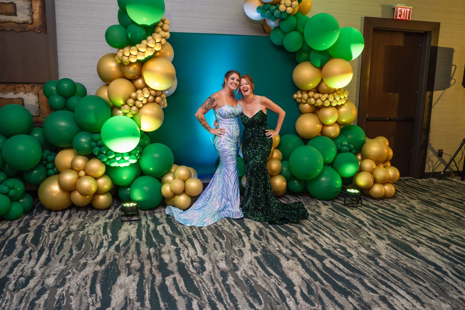 Elegant balloon arch display with green and gold balloons creates a festive party atmosphere in an indoor venue.