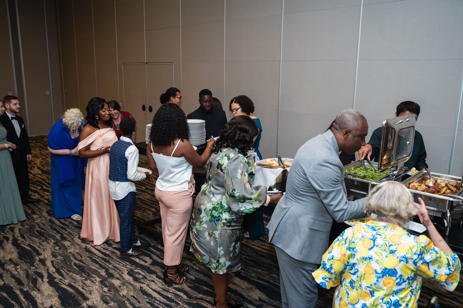 A group of people gathered at a social event, mingling and conversing in an indoor space.