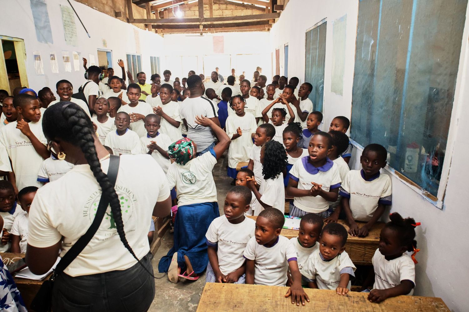 Large group of students in white uniforms gathered in a crowded classroom.