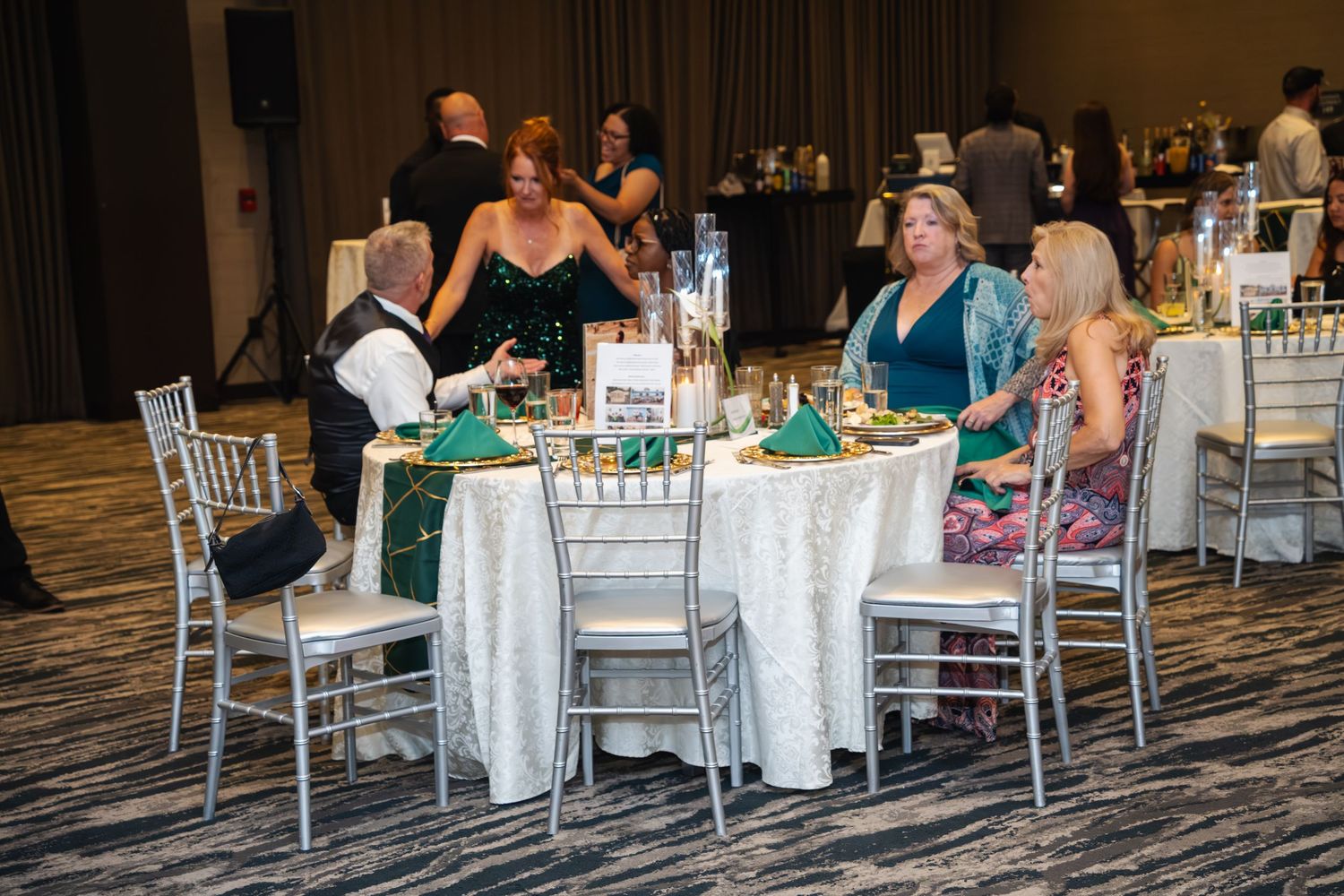 Wedding guests seated at elegant round tables with white linens and centerpieces in a luxurious banquet hall.
