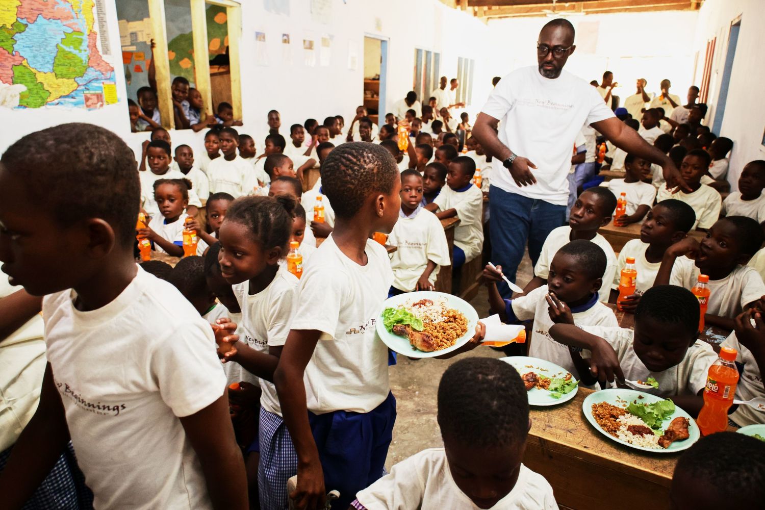 Students gathering around tables for lunch service in a school cafeteria.