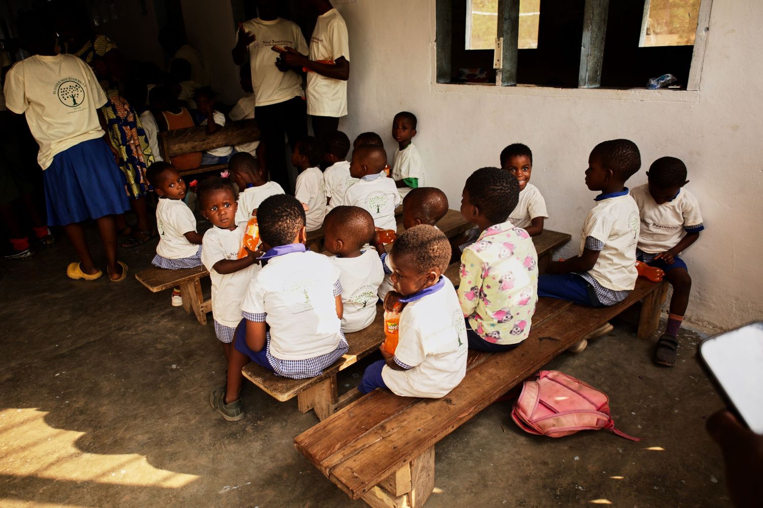 Students in white uniforms sitting on benches during lunch period.