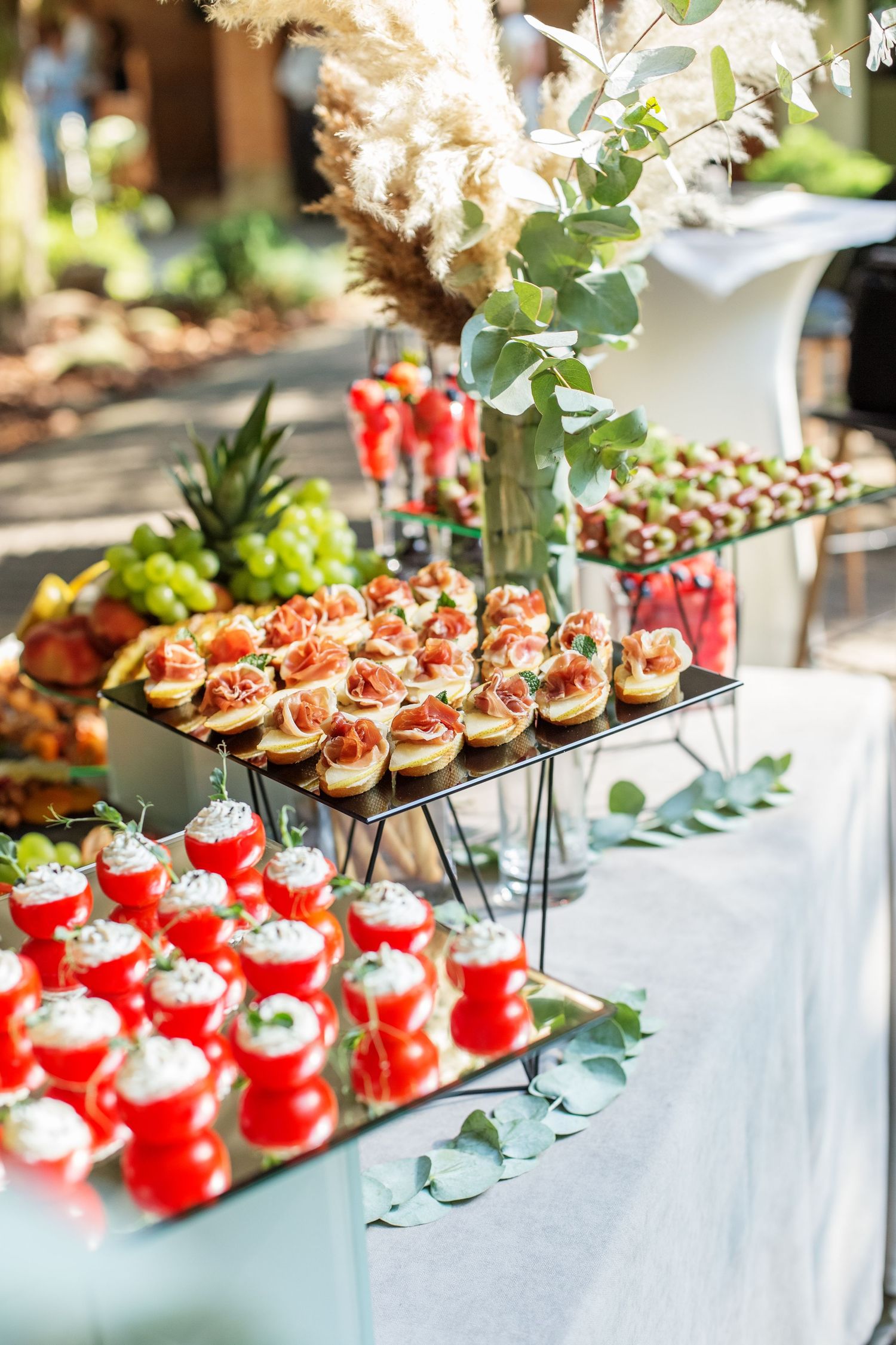 Beautifully arranged catering display with tiered appetizers and floral decorations.