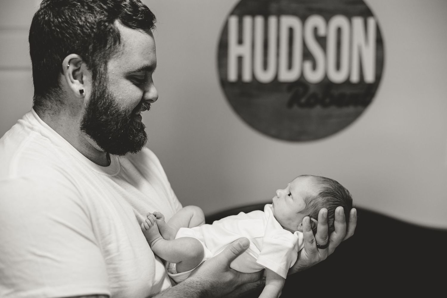 Bearded father holds newborn baby boy Hudson Robert in black and white photo.