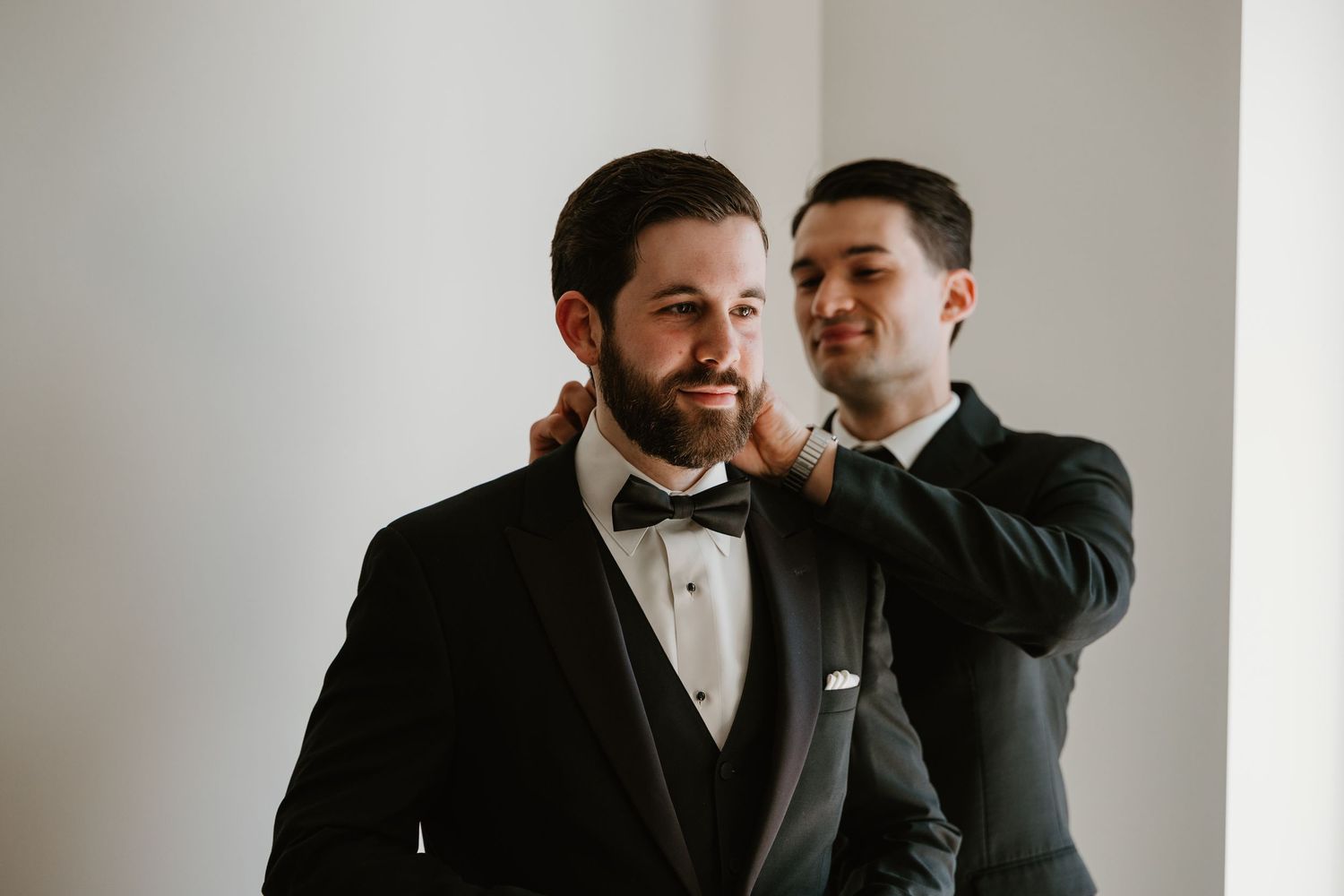 Groomsman adjusting the grooms bow tie before the wedding ceremony.