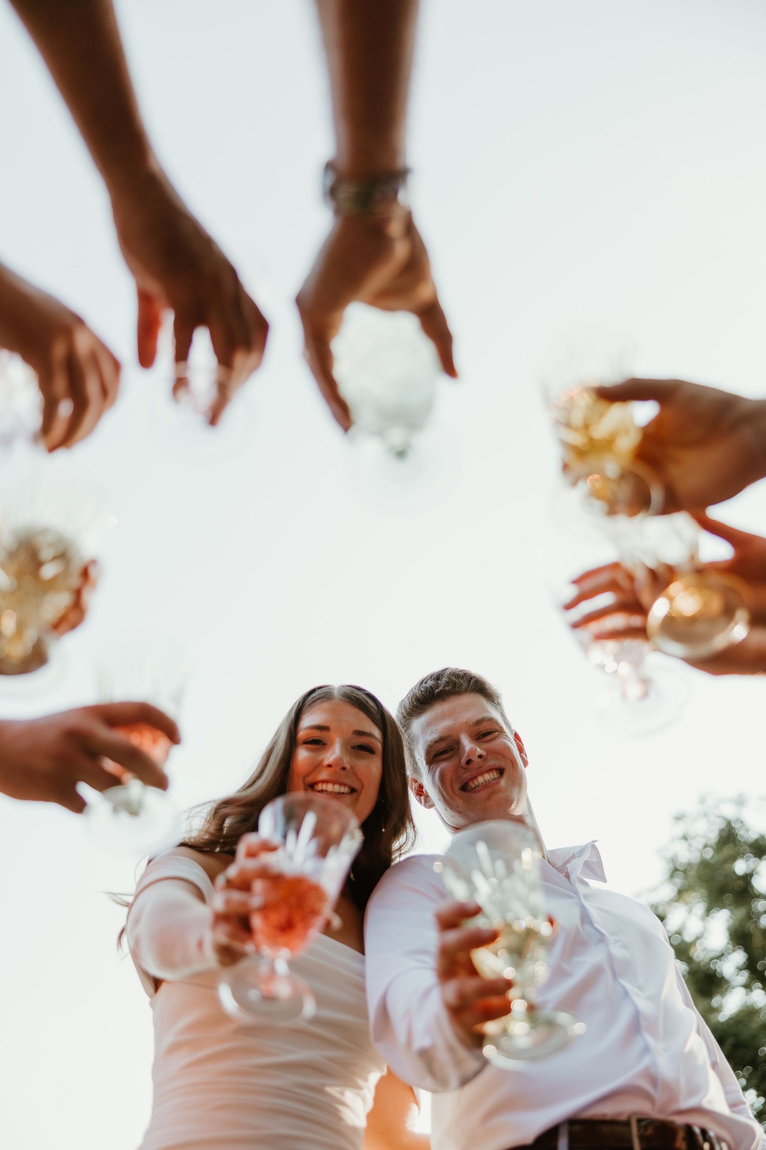 Bride and groom toasting champagne with wedding guests in a joyful outdoor celebration.