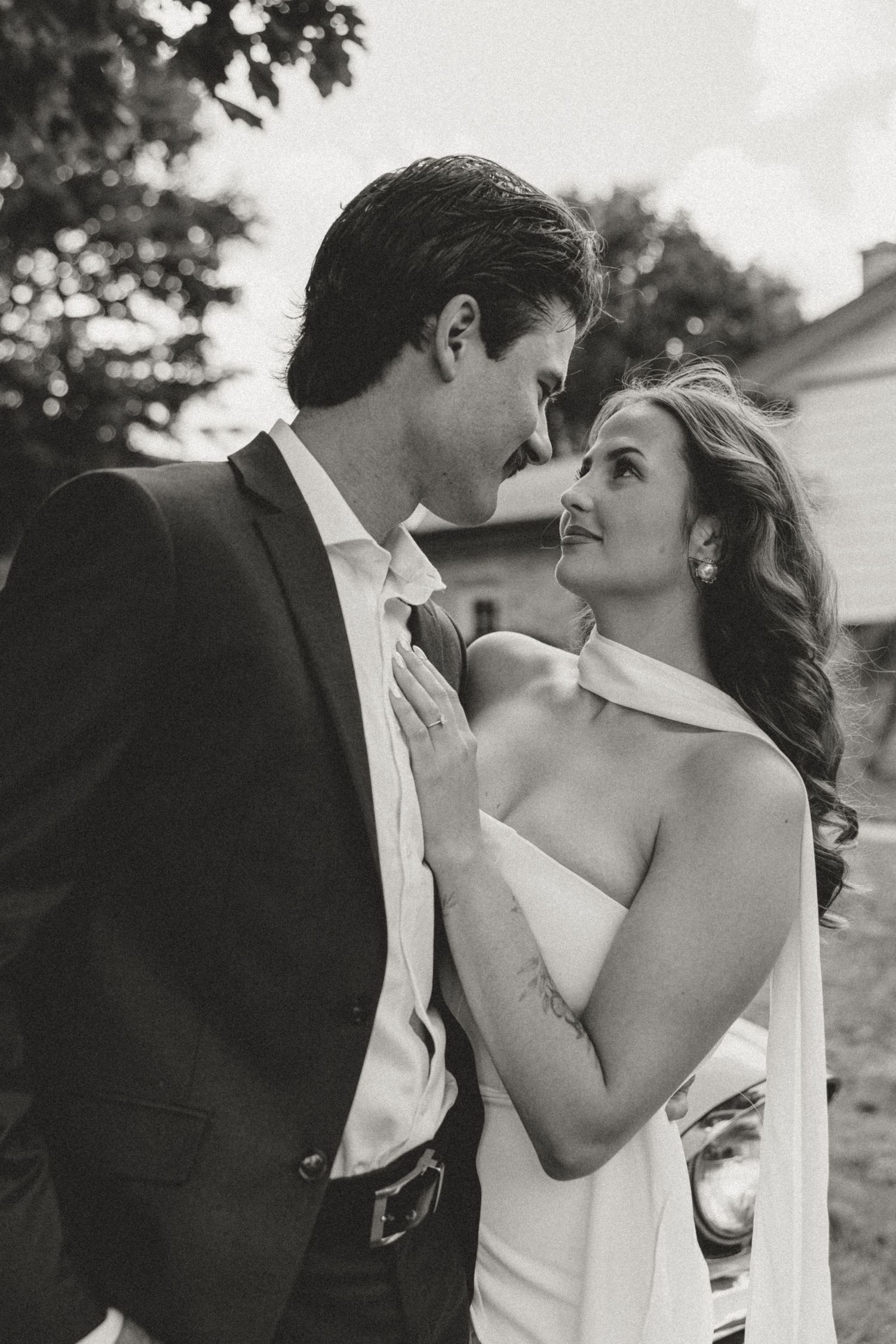 A bride and groom share an intimate black and white moment outdoors on their wedding day.