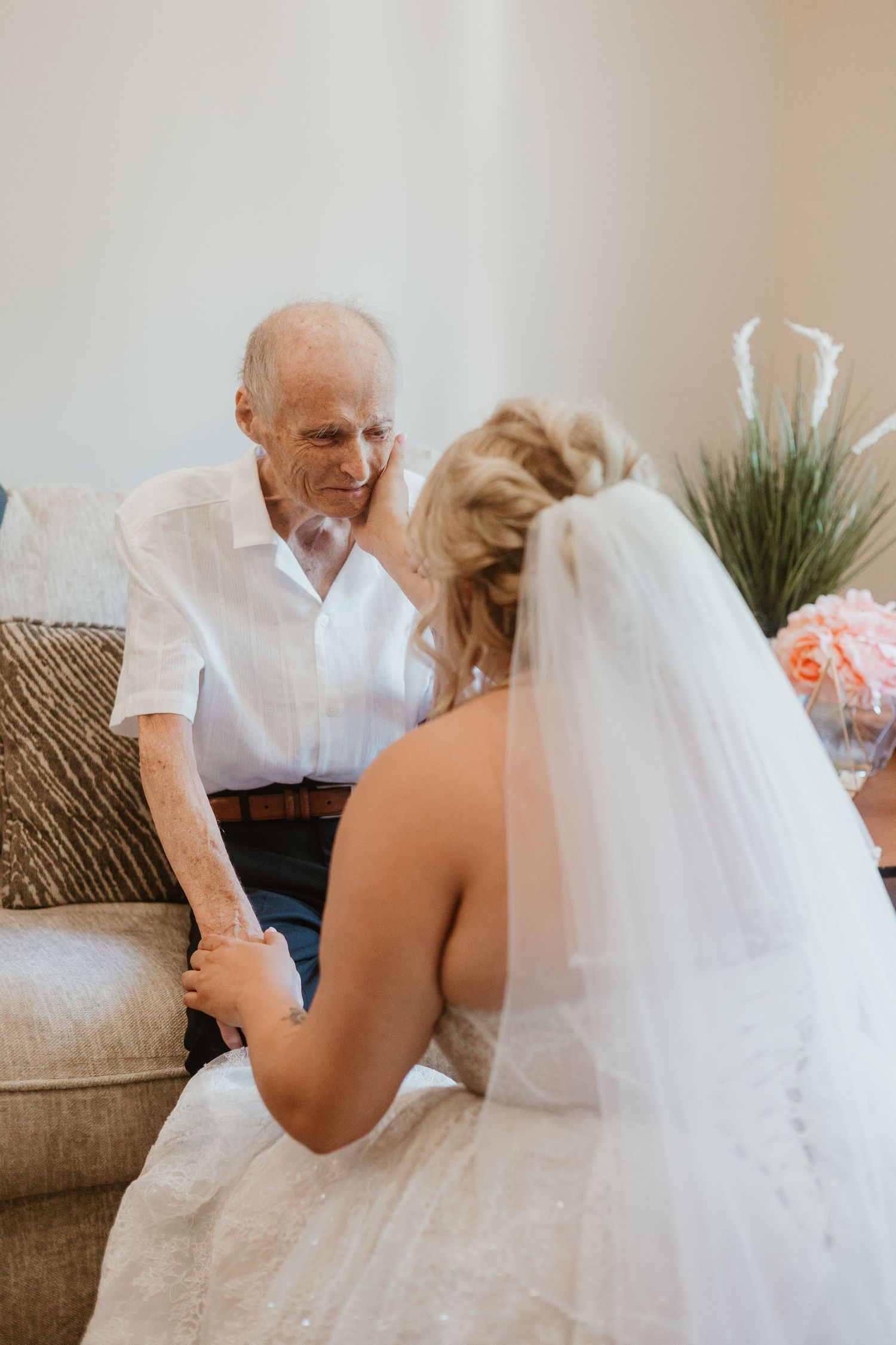 Emotional bride in wedding gown holding hands with elderly grandfather on her wedding day.