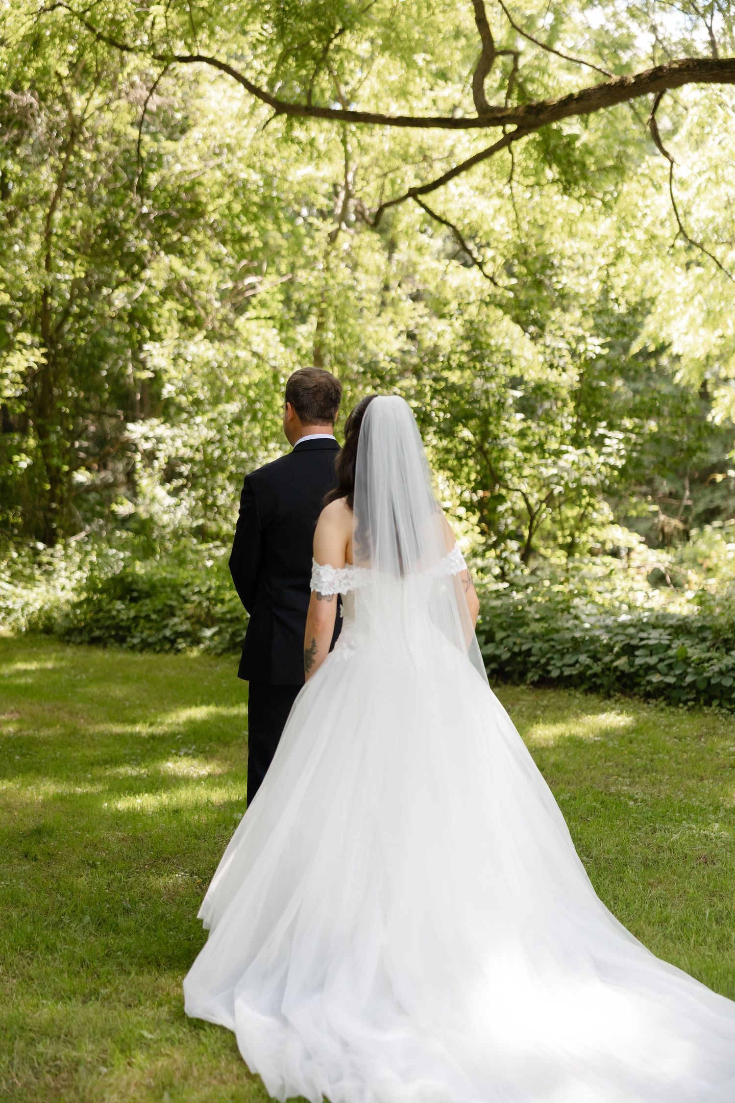 Bride and groom walking hand in hand through lush green garden after outdoor wedding ceremony.