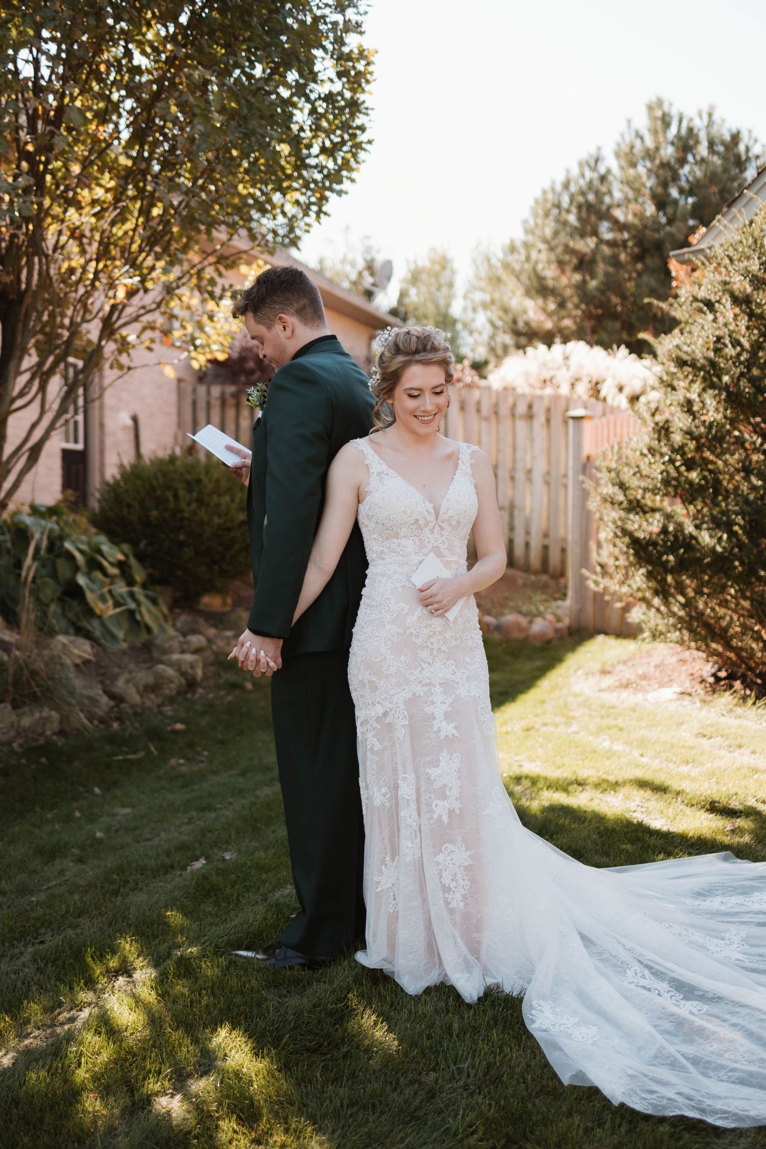 Groom reads private vows to smiling bride during backyard first look wedding moment.