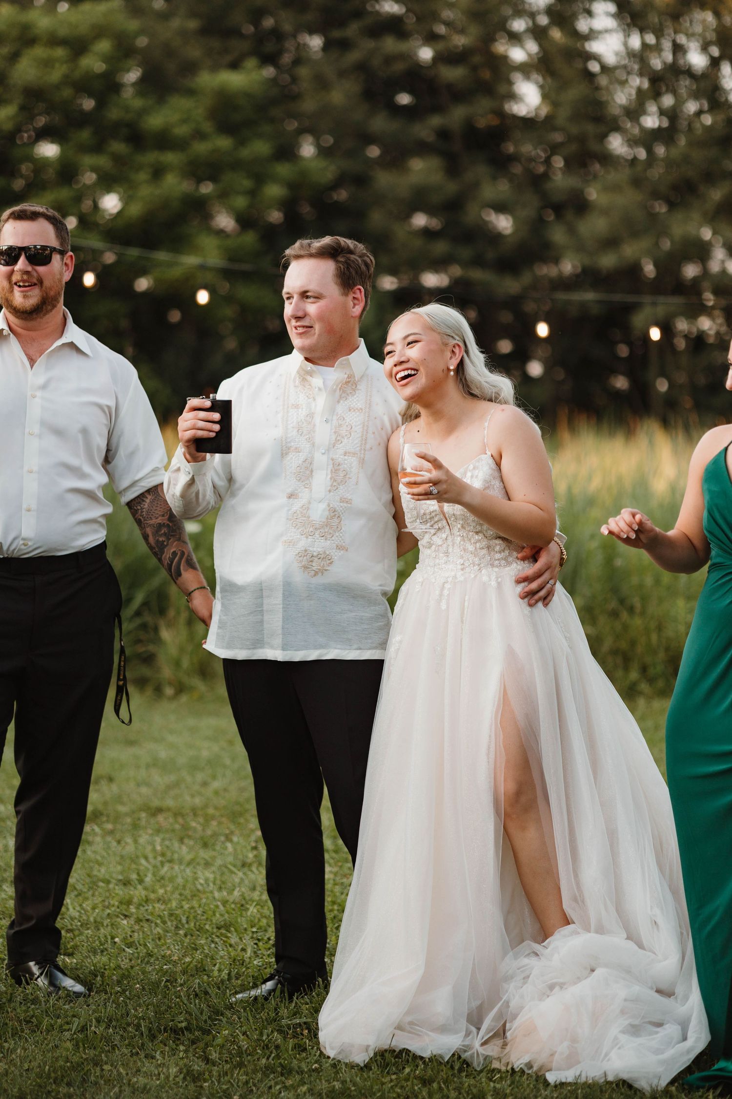 Bride and groom laughing joyfully with guests during outdoor wedding reception.