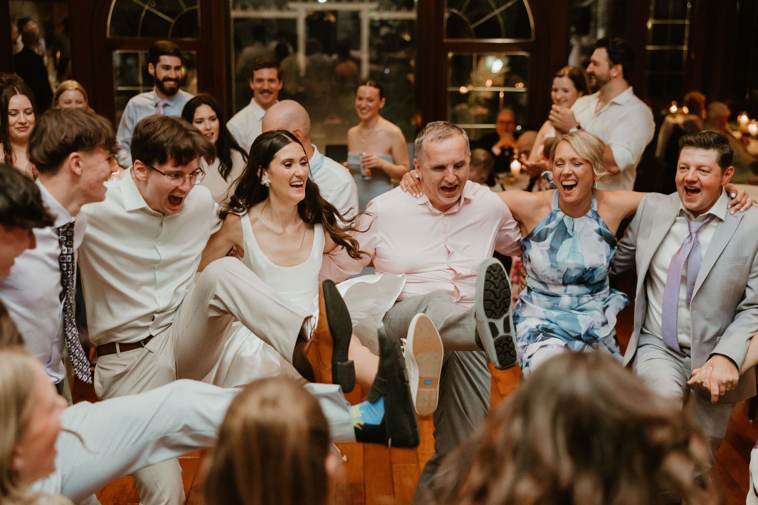 Wedding guests laughing and dancing together in lively reception celebration.