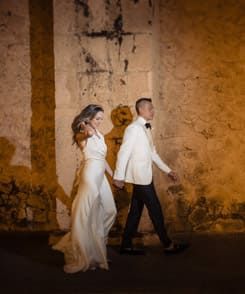 Cartagena wedding photographer capturing newlyweds walking at night by an illuminated colonial wall in the walled city