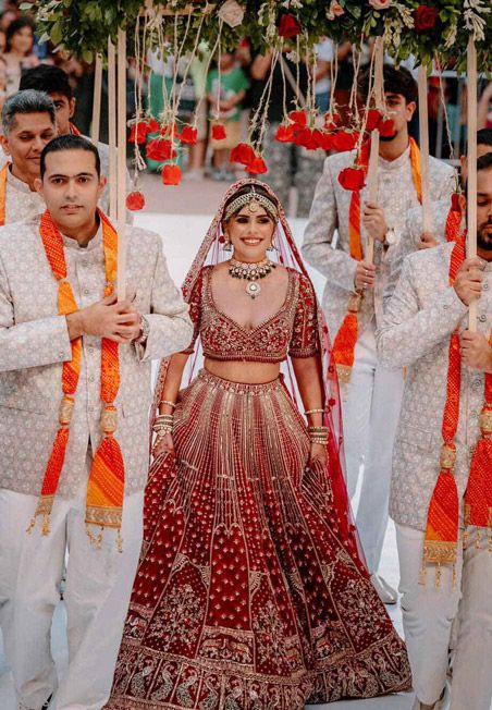 Cartagena wedding photographer capturing Indian bride entrance under phoolon ki chaadar, red lehenga and traditional jewelry