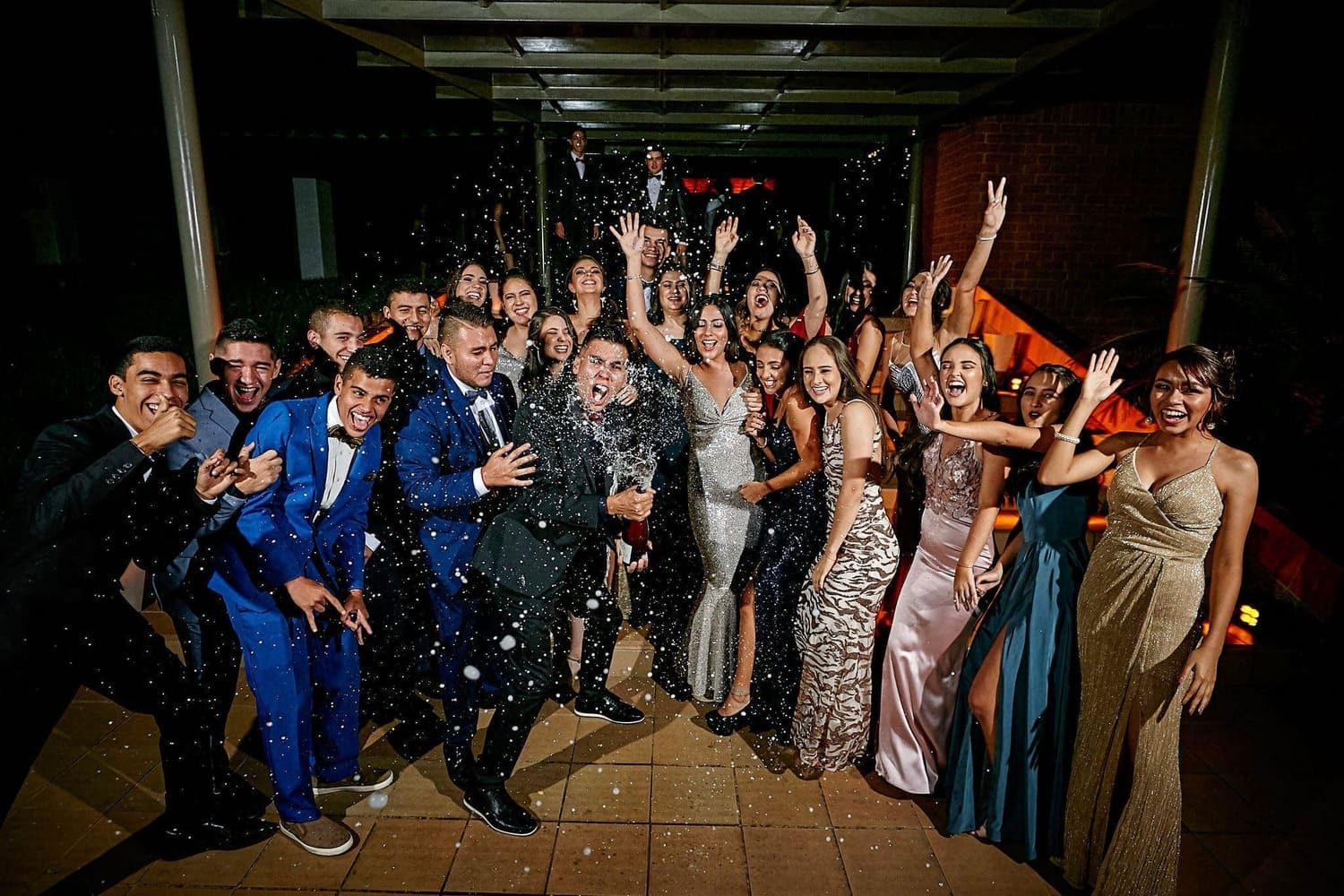 grupo de estudiantes celebrando fiesta prom de graduacion con trajes de gala y alegria