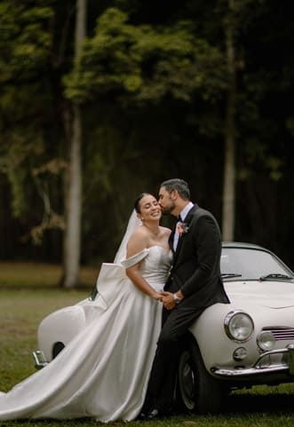 Cartagena wedding photographer capturing bride and groom by a classic car in a garden, romantic moment