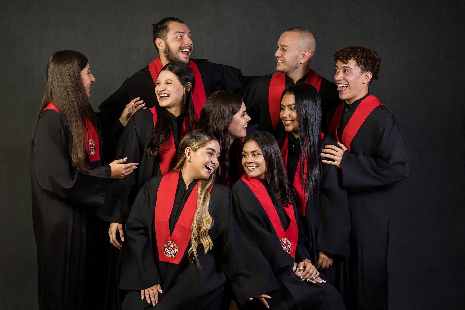 A group of people wearing black clothing with red scarves laugh together during a formal portrait session.
