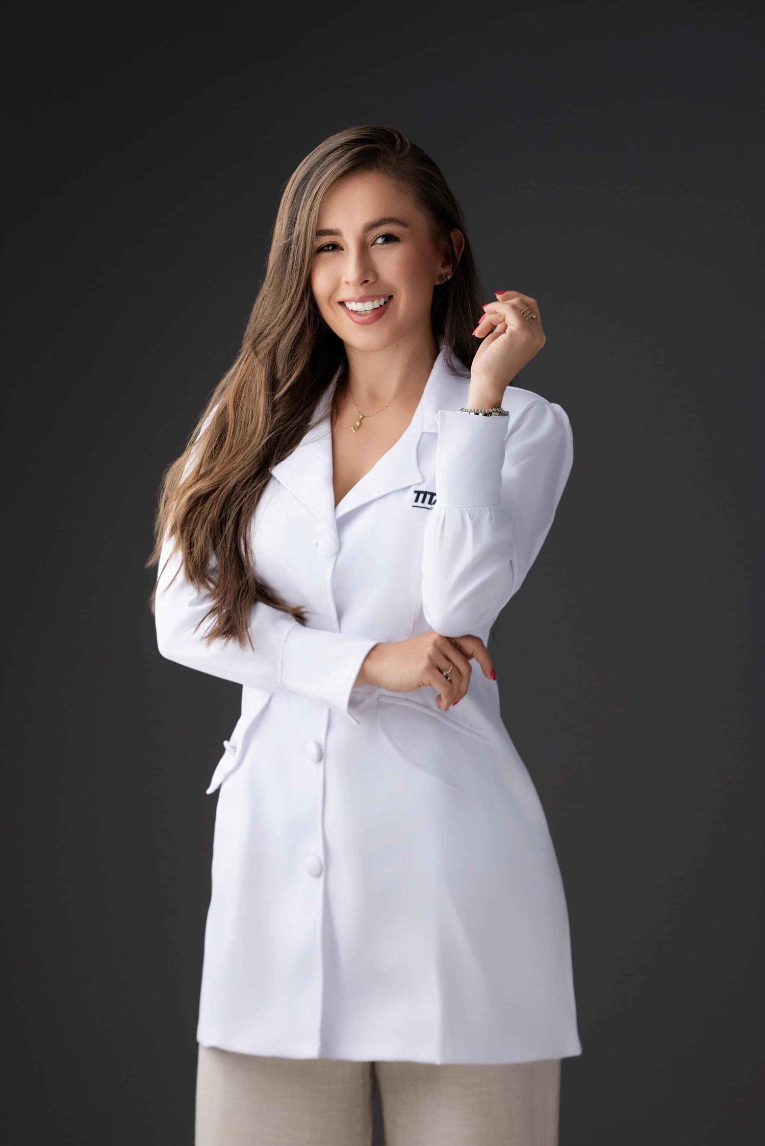 Mujer profesional con bata médica blanca sonriendo con confianza en un entorno de estudio en Pereira — John Palacio