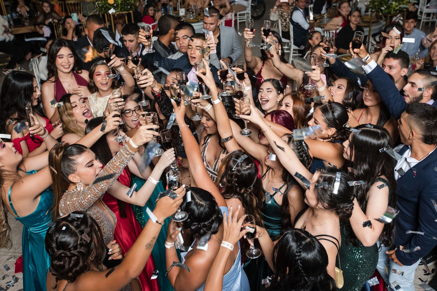 Crowd of excited people dancing and celebrating at a lively party with their hands raised in the air.