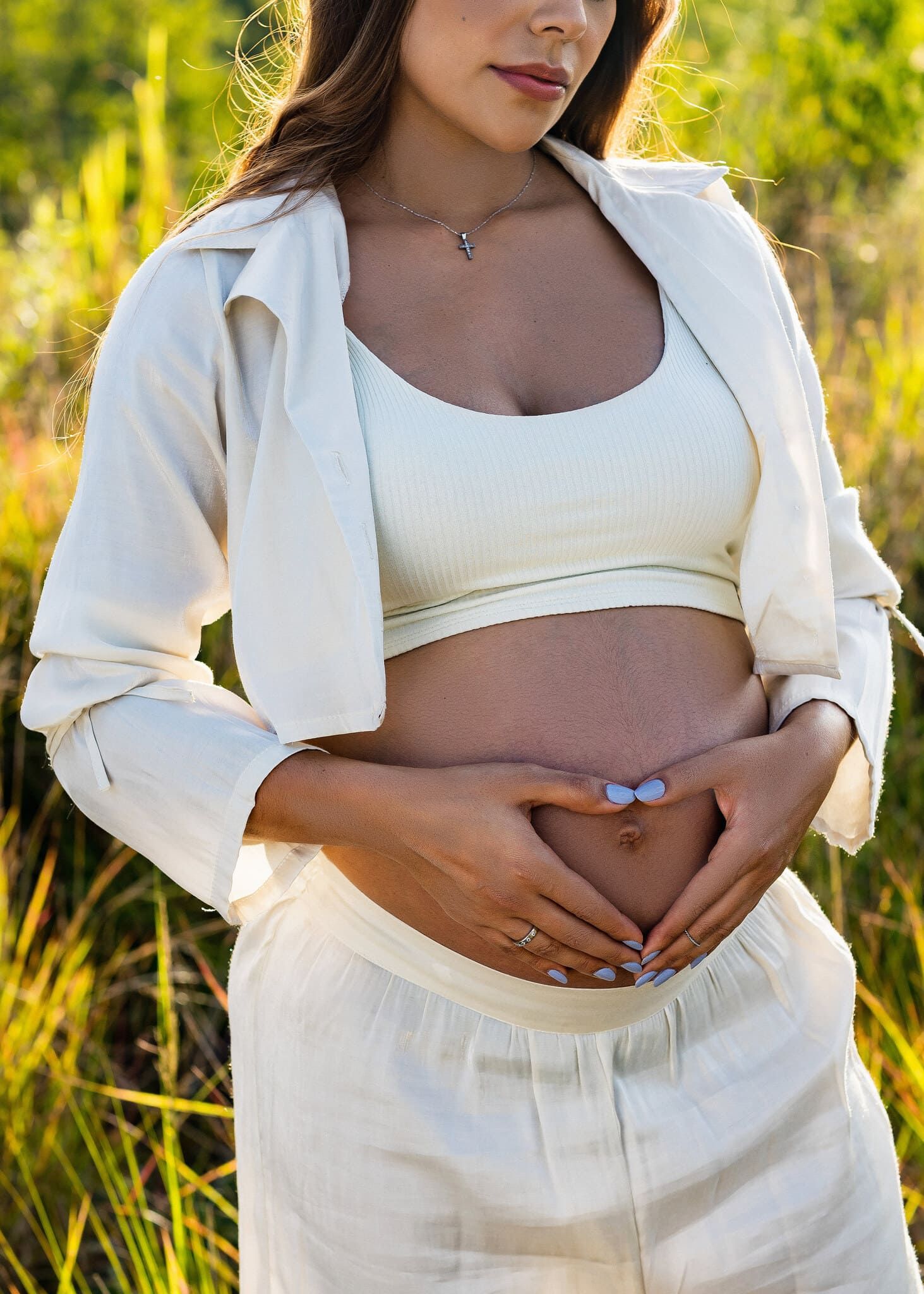 retrato de mujer embarazada mostrando su barriga en el campo en sesion de fotos de maternidad por john palacio