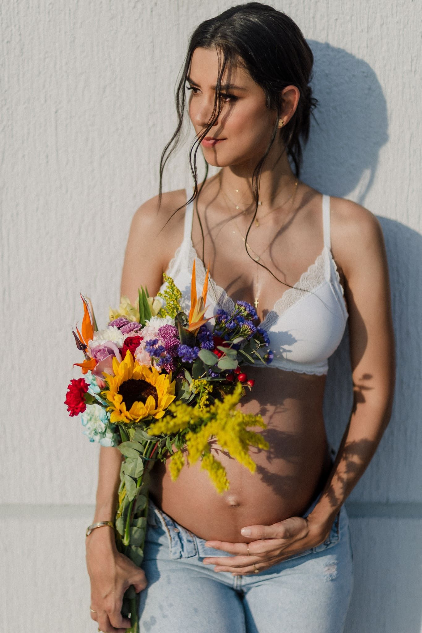 retrato de mujer embarazada con ramo de flores mirando de lado en sesion de fotos de maternidad por john palacio