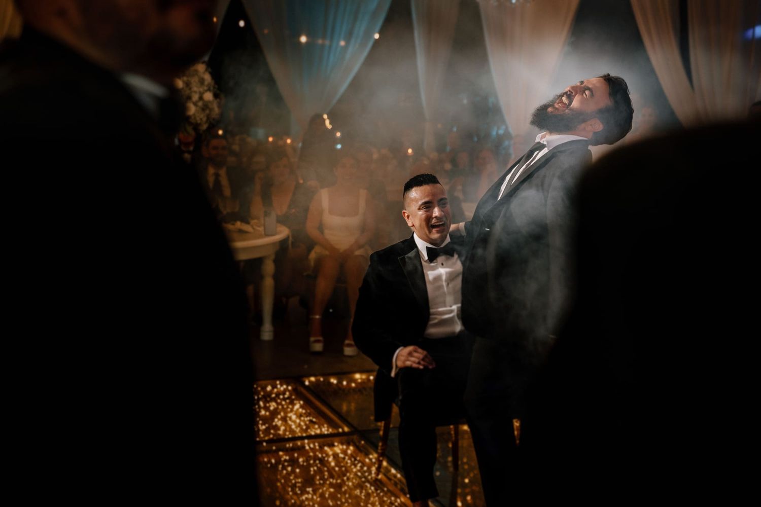 Hombres en esmoquin disfrutando un momento divertido durante la fiesta de boda.